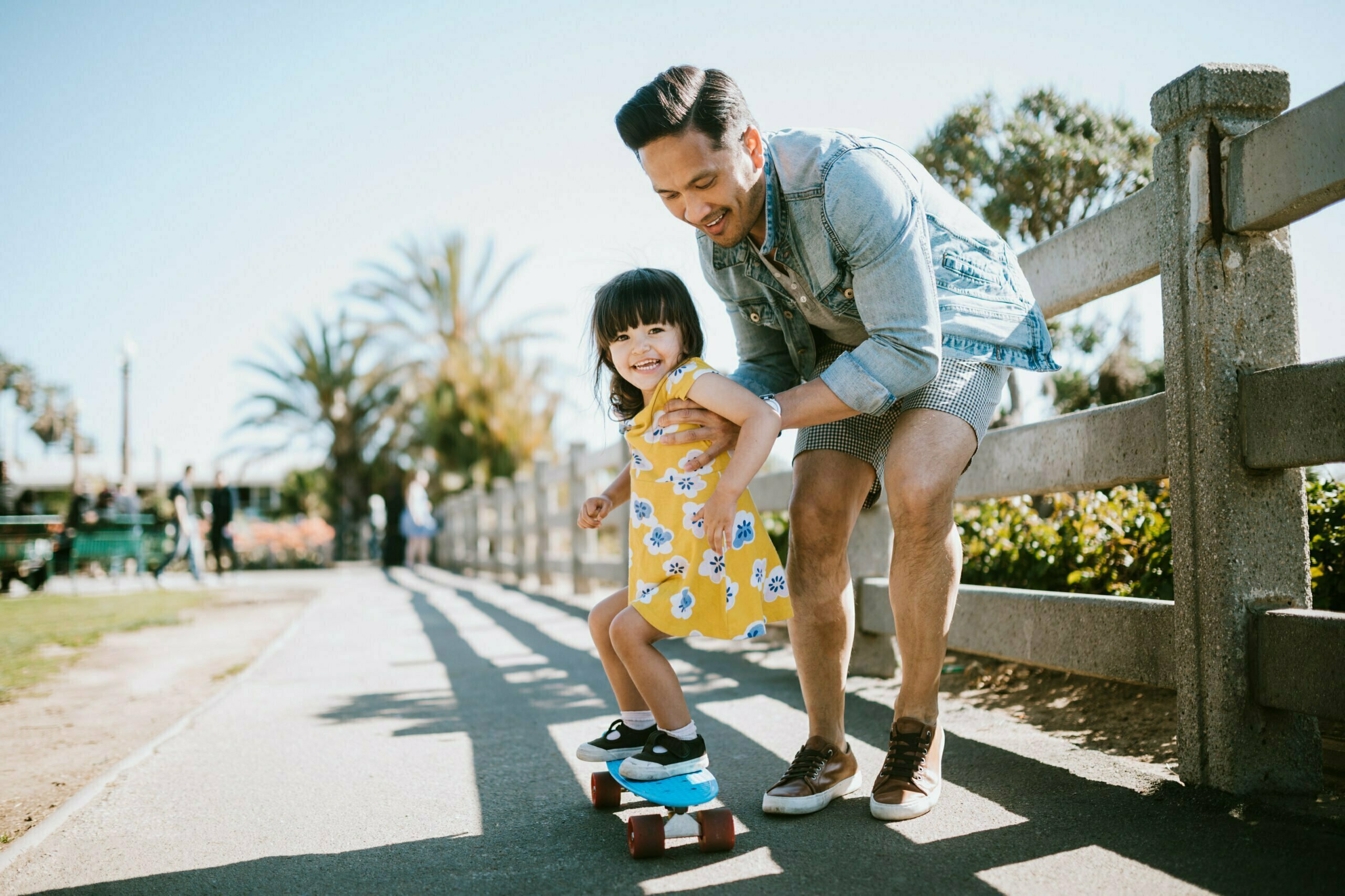 Father Helps Young Daughter Skateboard